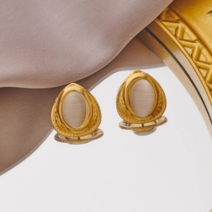 Detail view of vintage water-drop earrings with white pearl inlay on golden hammered metal