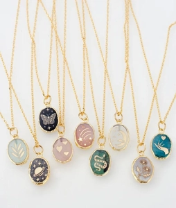 Detail of vintage gold-plated pendants with butterfly and moon patterns on fine chains