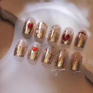 Detailed macro view of champagne gold nail art with red heart and gold moon motifs