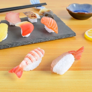 Detailed macro view of lifelike PVC salmon and shrimp sushi models on a wooden table