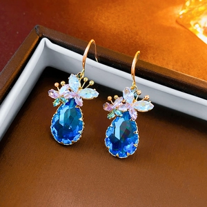 Macro view of blue drop zircon earrings with small floral crystals on gold hooks