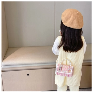 Detailed back view of a girl wearing a pink tweed handbag with pearls and lace trim