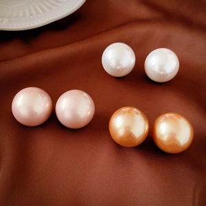 Three pairs of elegant faux pearl stud earrings in white, pink, and orange on silk fabric