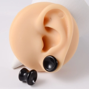 Detailed view of black concave stone ear gauges plug on realistic ear model