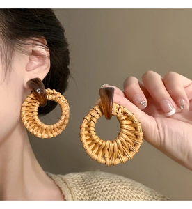 Detailed view of handmade round rattan drop earrings worn by a model in natural light