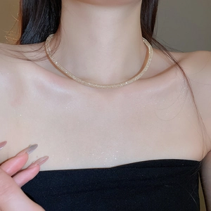 Close-up of golden mesh choker necklace with sparkling texture on a female neck