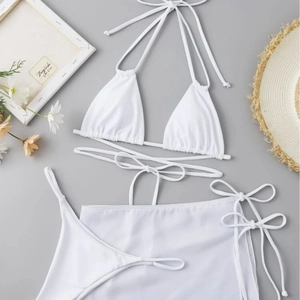 Three-piece white bikini set with halter top, string bottoms and wrap skirt