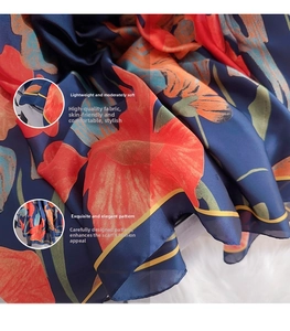 Close-up of floral print silk scarf featuring navy blue fabric with orange flower patterns