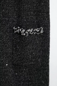 Vue détaillée du tissu en tweed noir avec des paillettes et des bordures en ruban tissé