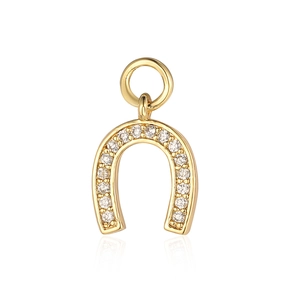 Macro shot of a golden horseshoe pendant with sparkling clear zircon stone inlay