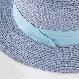 Detailed texture of blue woven straw sun hat with decorative satin ribbon band