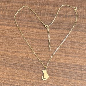 Gros plan d'un collier plaqué or 18 carats avec pendentif chat sur un fond en bois brun
