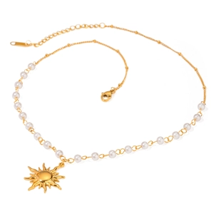 Collana con ciondolo sole dorato in acciaio inossidabile e perle su fondo bianco