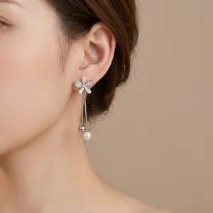 Elegant flower stud earrings with pearl tassel drops and silver finish on female model