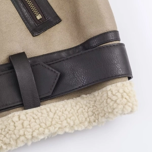 Detail of dark brown faux leather jacket with cream fleece lining and adjustable buckles