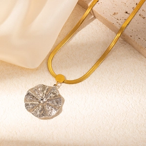 Detail of silver irregular floral pendant on a gold snake chain necklace