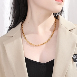 Close-up of a gold-plated stainless steel coffee bean link chain worn by a female model