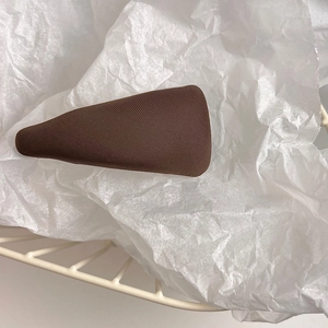 Close-up of a soft brown sponge fabric hair clip on white textured paper with a basket