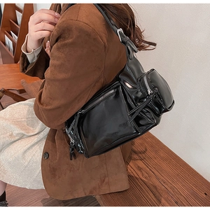 Détail de la boucle argentée ajustable et des poches zippées sur un sac noir brillant