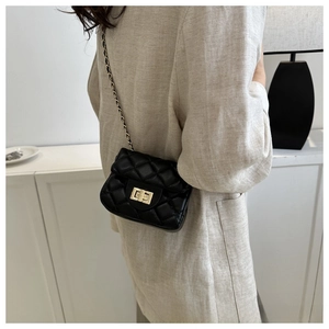 Close-up of quilted black mini bag featuring gold twist lock and chain strap detail