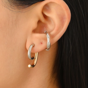 Close-up of minimalist silver bamboo cuff and gold J-shaped earring on model ear
