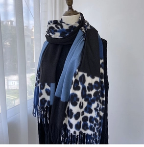 Detail of winter scarf showing blue leopard print, color blocking, and fringe texture