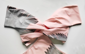 Detail of twist-front bikini top with pink tropical palm leaf print and smooth finish