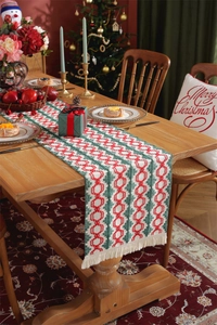 Detail of red and green knitted Christmas table runner with tassels on a wooden table