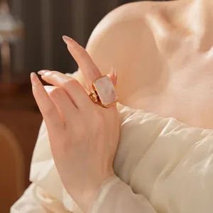 Elegant woman wearing a large rectangular pink stone ring in a gold-plated setting