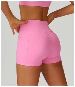 Detail view of pink high-waisted yoga shorts with side pocket and V-shaped back seam detail