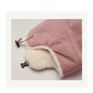 Detail of pink corduroy winter hat with soft white faux fur lining and buckle strap