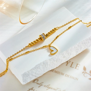 Double-layered gold chain necklace featuring heart shell pendant and zircon beads on stone