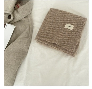 Detailed close-up of brown knit wool scarf texture with a minimal egg woven label