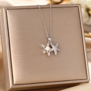 Elegant starfish pendant necklace with pearl and rhinestones on a gold jewelry box