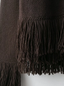 Gros plan détaillé sur un tricot marron foncé avec des finitions décoratives à franges