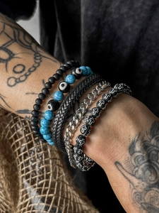 Close-up of four-piece beaded bracelet set featuring blue evil eye and silver cross charms