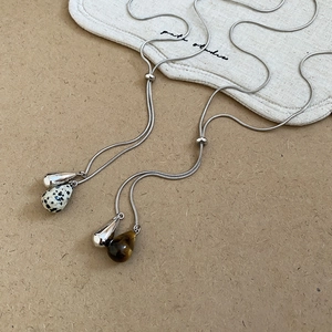 Detail of adjustable metal snake chains with tiger eye and dalmatian jasper pendants