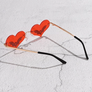 Detail of red heart sunglasses with black bat pattern and golden metal frame