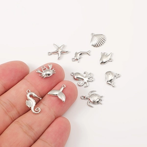 Nine stainless steel silver ocean charms including seahorse, turtle and starfish on white