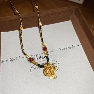 Dettaglio della collana in stile cinese con ciondoli a zucca dorati e perline rosse