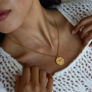 Detail of 18K gold stainless steel coin necklace with bee relief worn by a model