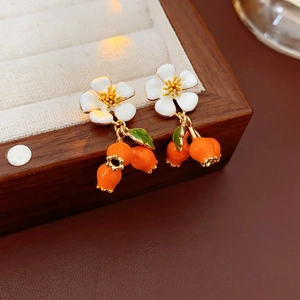 Detail of vintage flower earrings with orange berries in a velvet wooden jewelry box