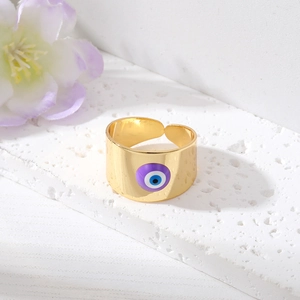 Gros plan détaillé d'une bague Evil Eye dorée avec émail violet sur surface texturée