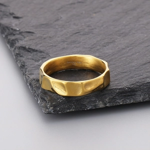 Detailaufnahme eines goldenen Edelstahlrings mit Textur auf schwarzem Stein
