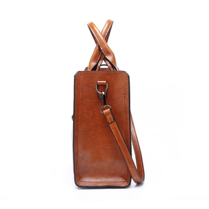 Brown leather tote bag for women showing a sleek side view with a metallic buckle and strap