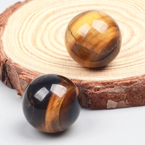 Polished natural tiger eye crystal spheres showcasing golden brown cat-eye texture on wood