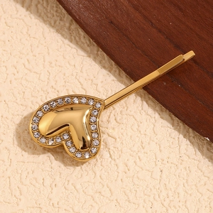 Macro detail of gold-plated 18K stainless steel heart hair clip with shiny rhinestones