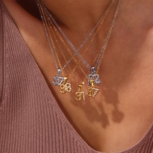 Close-up of model wearing 18K gold and silver year number pendants with micro-set zircons