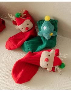 Detail of red and green knitted Christmas socks with 3D plush reindeer and tree charms