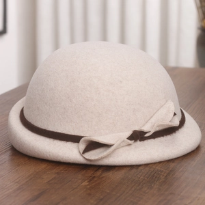 Detailed texture of beige wool beret with brown suede bow on vintage wooden surface